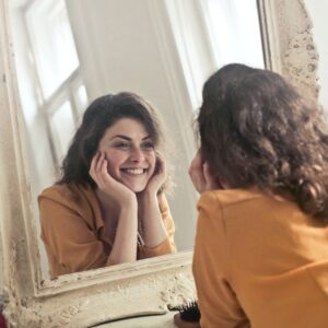 woman staring in mirror smiling